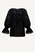 Black blouse with sheer sleeves on a light gray background