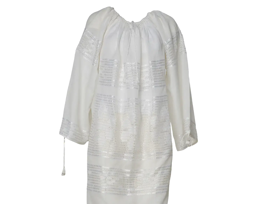 A long white or off-white dress with three-quarter sleeves and horizontal embroidered or lace-like bands across the bodice and skirt, shown against a plain white background.