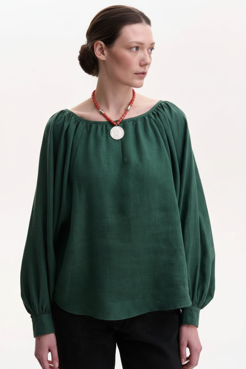 Woman wearing a green blouse with long sleeves on a white background