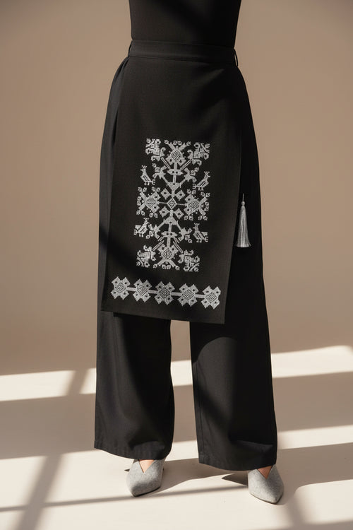 Black garment with white folk embroidery on a white background