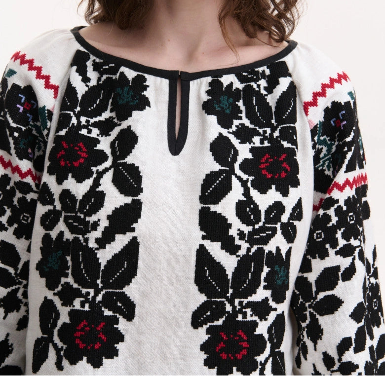 Front view of women’s hand-embroidered Vyshyvanka blousewhite embroidered top with black floral patterns and red accents. Blouse Roumaine Shop