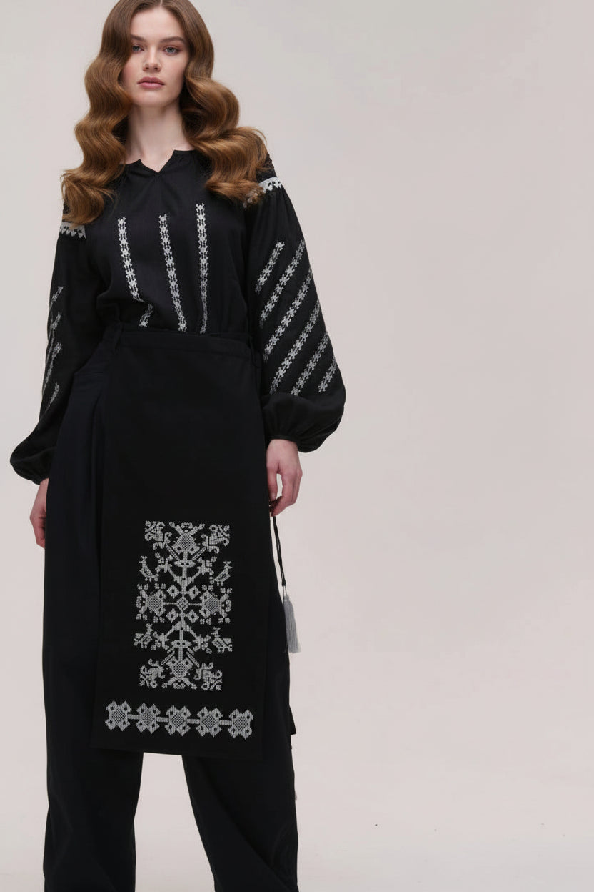 Black outfit with white embroidery on a plain background