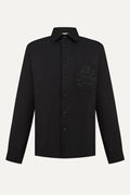 Black shirt with a floral embroidery on the chest against a white background