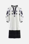 White dress with black and blue embroidery on a white background