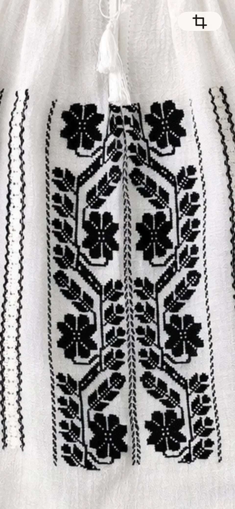 Close-up of a white garment with black floral embroidery