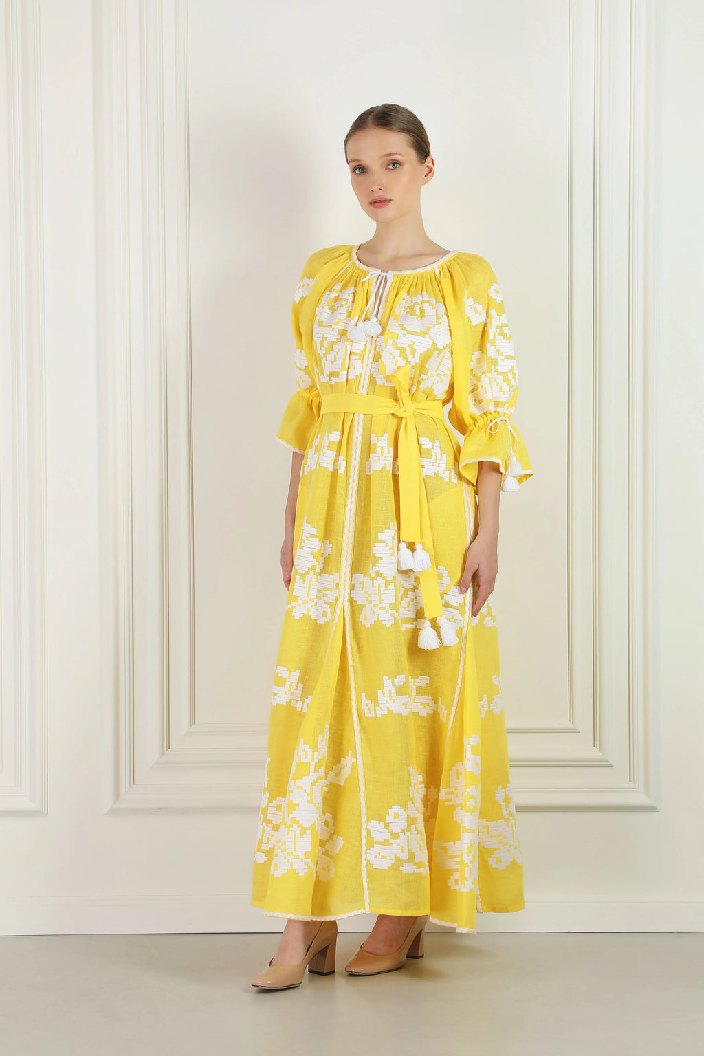 Woman wearing a yellow floral dress against a white background