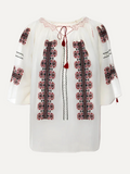 White blouse with red and black embroidery on a gray background