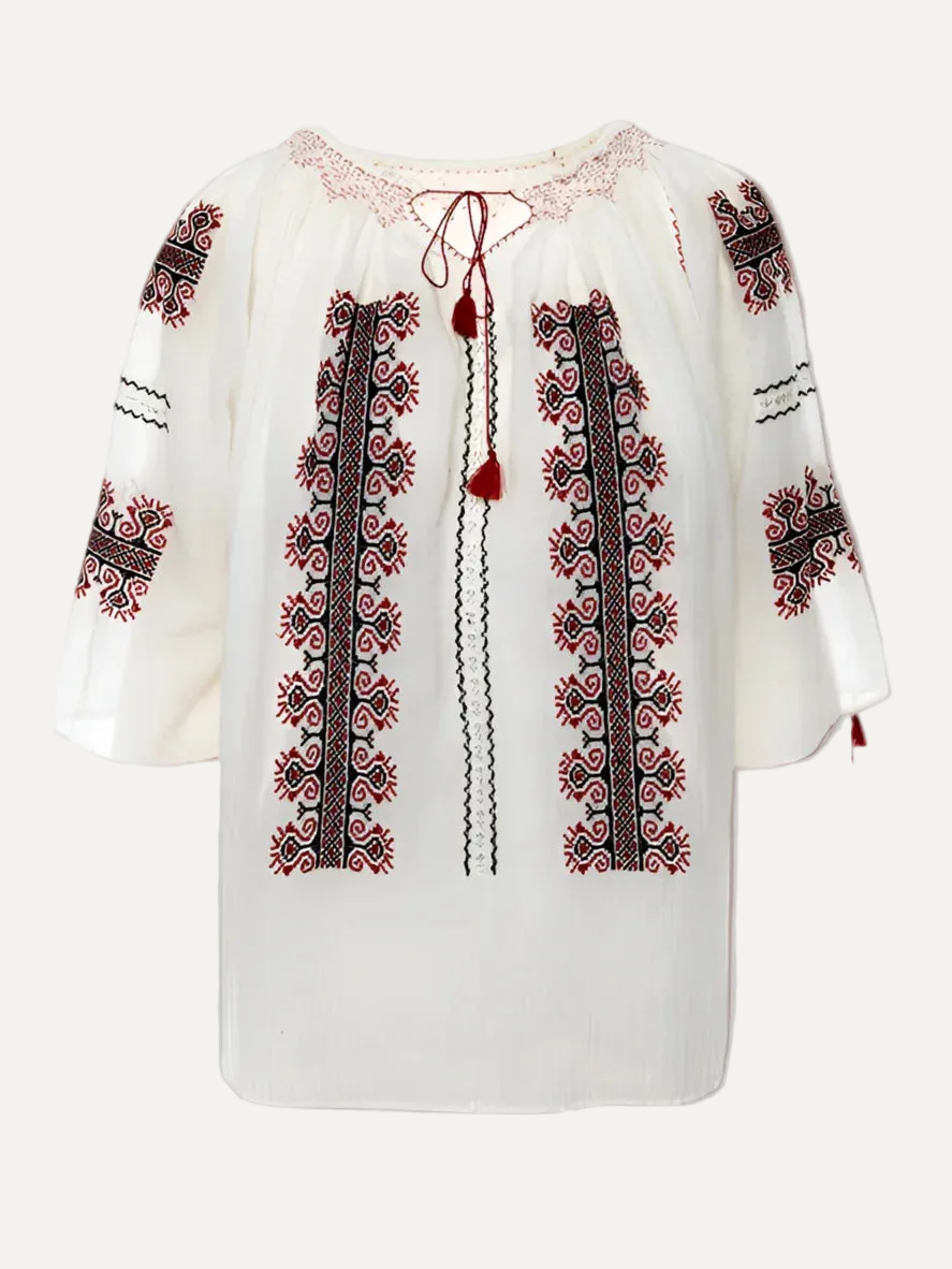 White blouse with red and black embroidery on a gray background