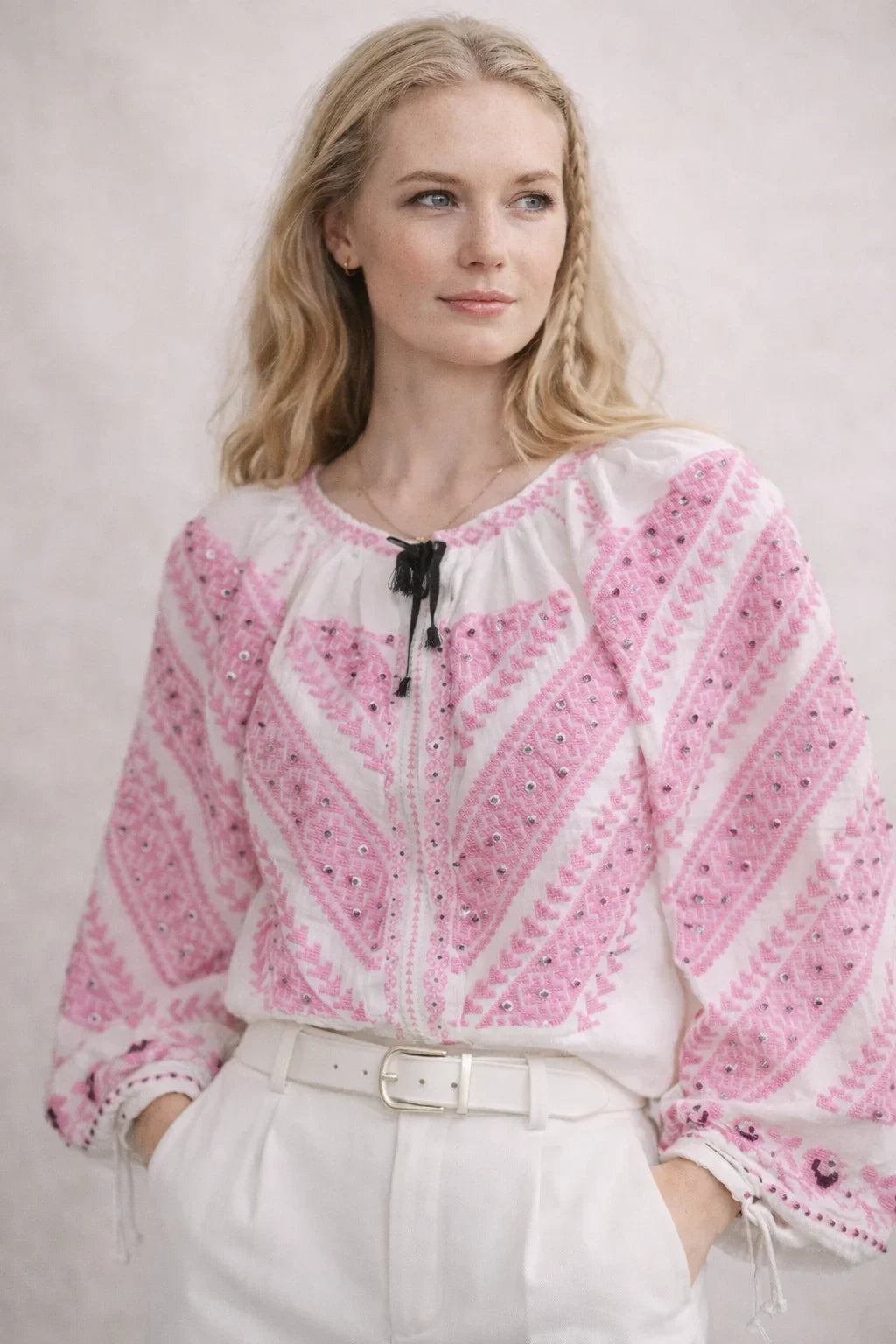 Woman wearing a pink and white patterned blouse against a plain background