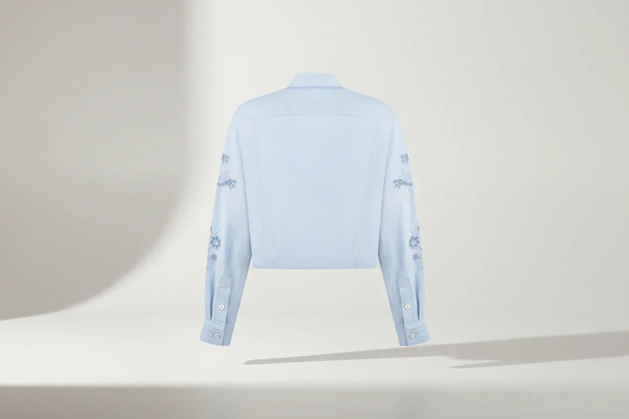 Light blue shirt with floral embroidery on a white background