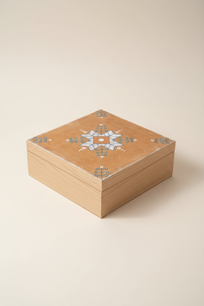 Christmans box e with a hand-painted geometric design, featuring a central starburst motif in light blue, white, and orange-brown, set against a solid dark green background.