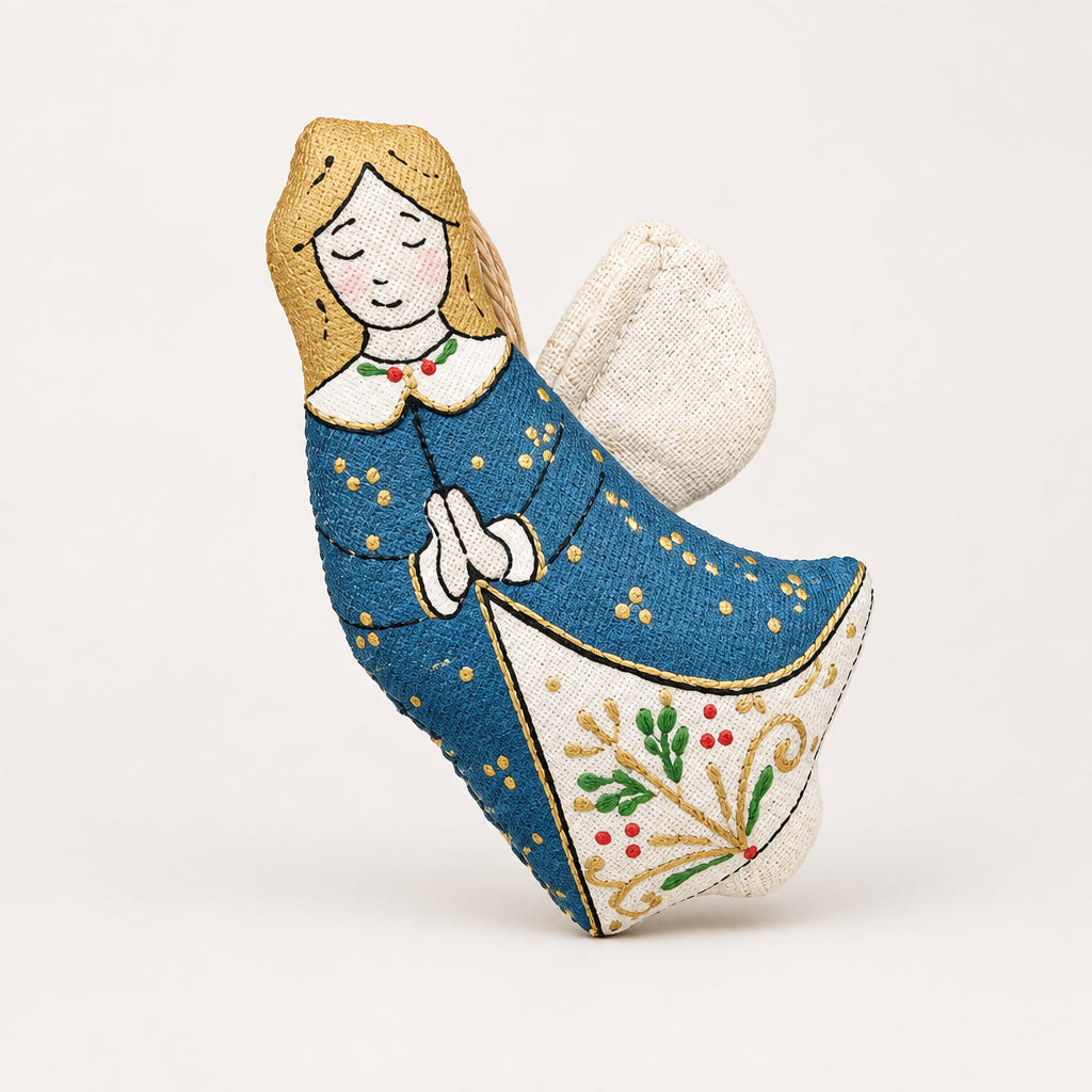 A handmade fabric Christmas angel ornament styled in a flat-lay holiday setting with pine branches, red berries, walnuts, star-shaped cookies. Blouse Roumaine Shop