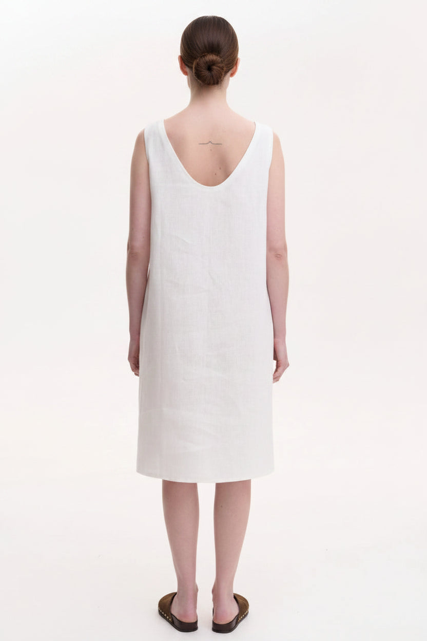 Person wearing a white sleeveless dress on a plain background