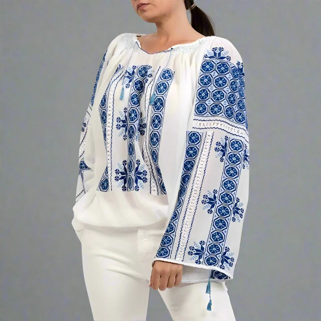 Woman wearing a white blouse with blue embroidery on a gray background