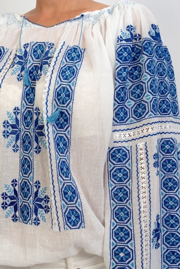 White garment with blue geometric embroidery