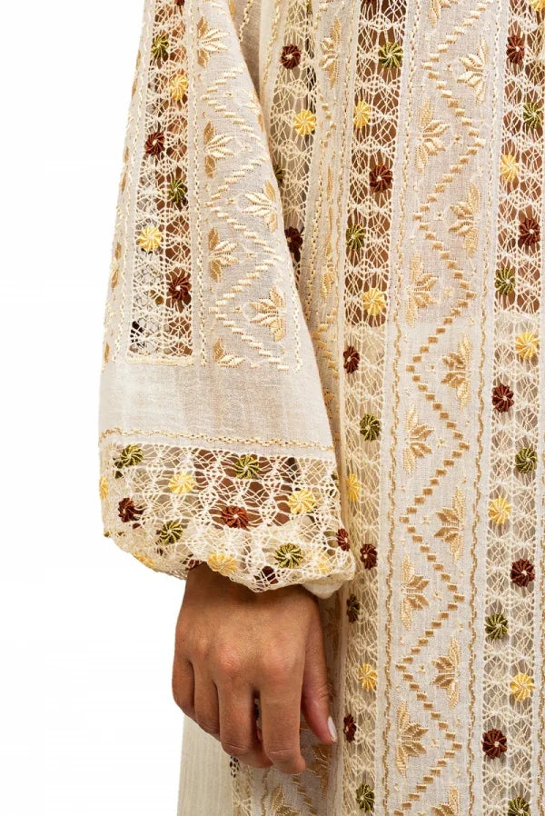 Close-up of a hand holding a piece of embroidered fabric with floral patterns.